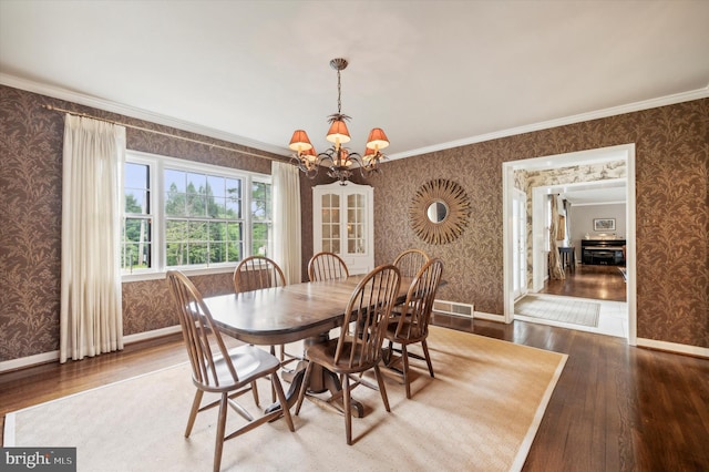 dining space with hardwood / wood-style flooring, ornamental molding, and a chandelier