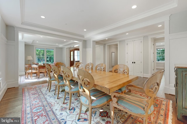 dining area with ornamental molding, light wood-type flooring, and a healthy amount of sunlight