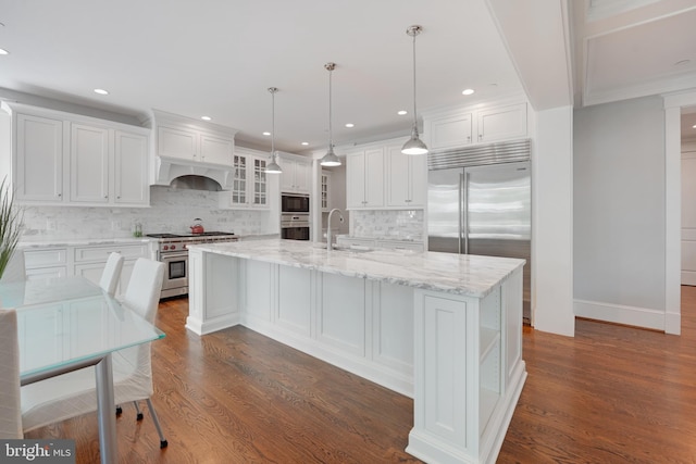 kitchen featuring sink, dark hardwood / wood-style floors, built in appliances, an island with sink, and white cabinets