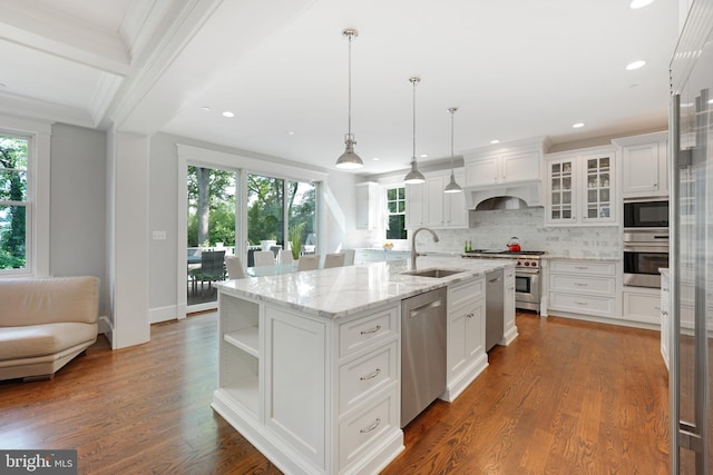 kitchen featuring a kitchen island with sink, hanging light fixtures, sink, appliances with stainless steel finishes, and white cabinetry