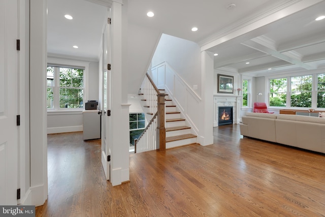 interior space with beam ceiling, light hardwood / wood-style floors, crown molding, and coffered ceiling