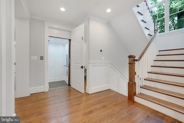 stairs featuring crown molding and hardwood / wood-style floors