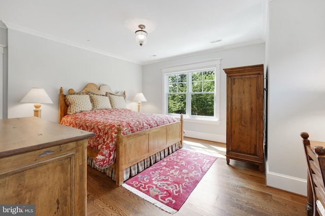 bedroom with dark hardwood / wood-style floors and crown molding