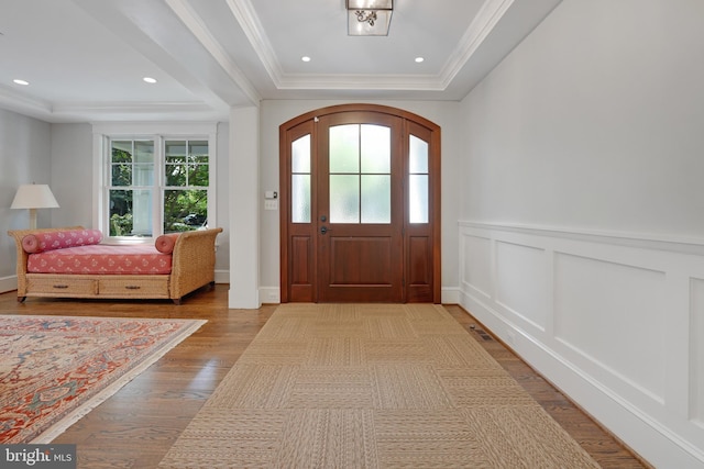 entrance foyer featuring a raised ceiling, crown molding, and light hardwood / wood-style floors