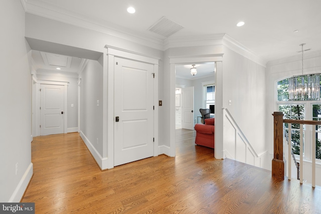 corridor featuring hardwood / wood-style floors, an inviting chandelier, and ornamental molding