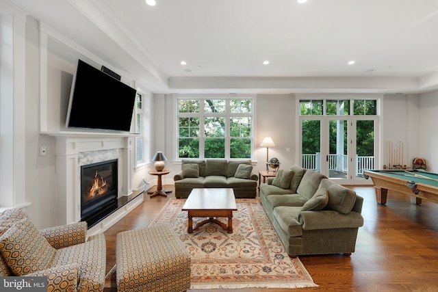 living room featuring hardwood / wood-style flooring, ornamental molding, a high end fireplace, and pool table