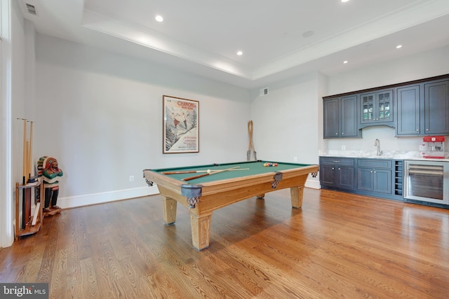 recreation room with light wood-type flooring, a raised ceiling, beverage cooler, wet bar, and pool table