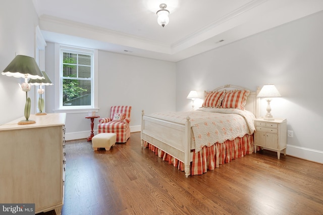 bedroom with a raised ceiling, wood-type flooring, and ornamental molding