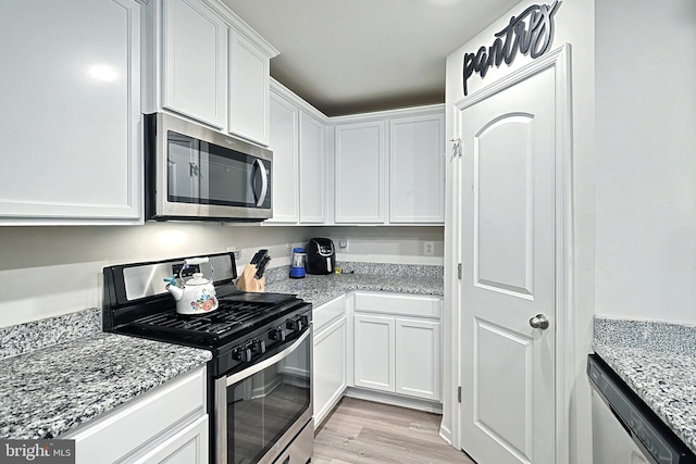 kitchen featuring white cabinets, light hardwood / wood-style floors, light stone counters, and appliances with stainless steel finishes