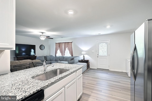 kitchen featuring stainless steel refrigerator, ceiling fan, sink, light stone counters, and white cabinets