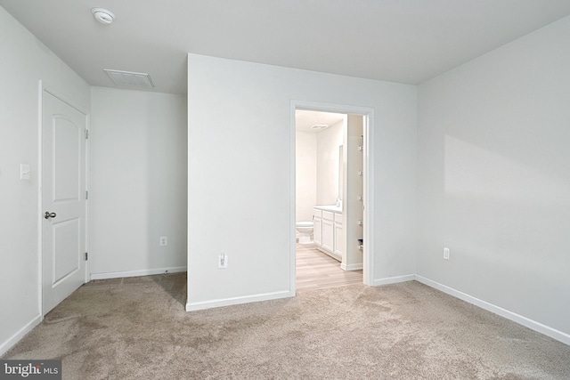 unfurnished bedroom with ensuite bath and light carpet