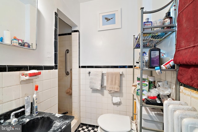 bathroom featuring toilet, radiator heating unit, tile walls, and tiled shower