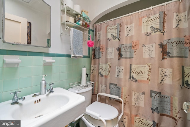 bathroom featuring toilet, tile walls, curtained shower, and sink