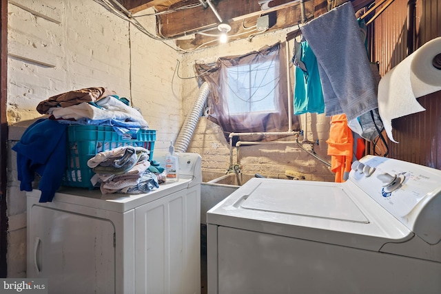 laundry room featuring washer and clothes dryer and brick wall