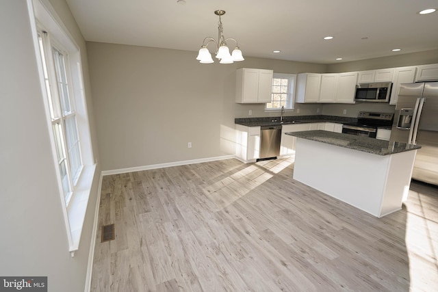 kitchen featuring a center island, stainless steel appliances, an inviting chandelier, pendant lighting, and white cabinets