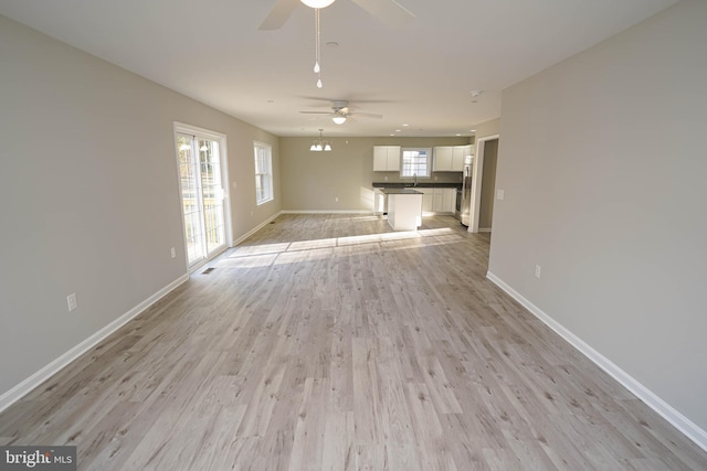 unfurnished living room with light hardwood / wood-style floors, ceiling fan, and sink