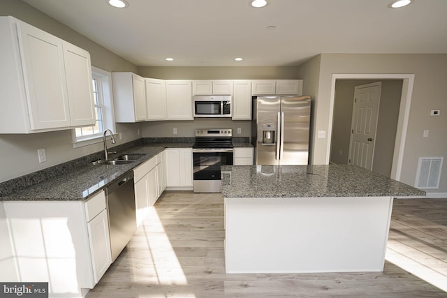 kitchen featuring white cabinets, stainless steel appliances, a kitchen island, and sink