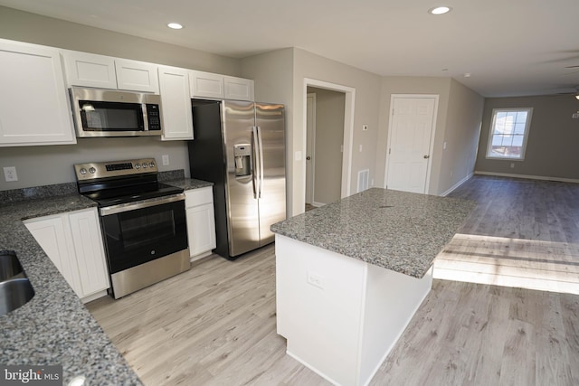 kitchen featuring white cabinets, appliances with stainless steel finishes, stone countertops, and light hardwood / wood-style floors