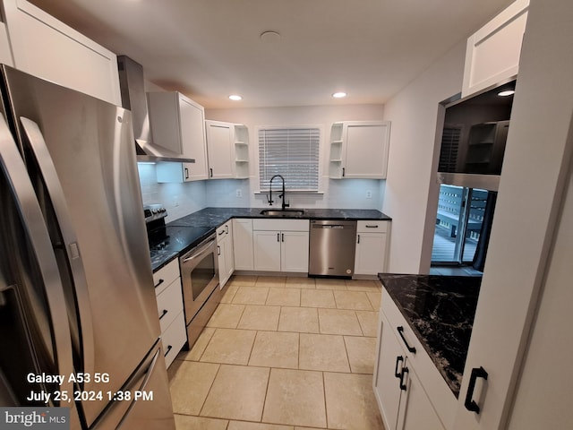 kitchen featuring sink, white cabinetry, appliances with stainless steel finishes, wall chimney range hood, and backsplash