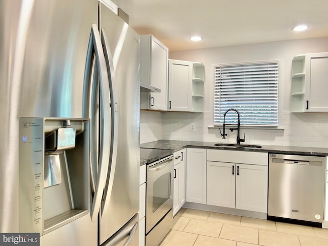 kitchen with tasteful backsplash, sink, white cabinets, light tile patterned floors, and stainless steel appliances