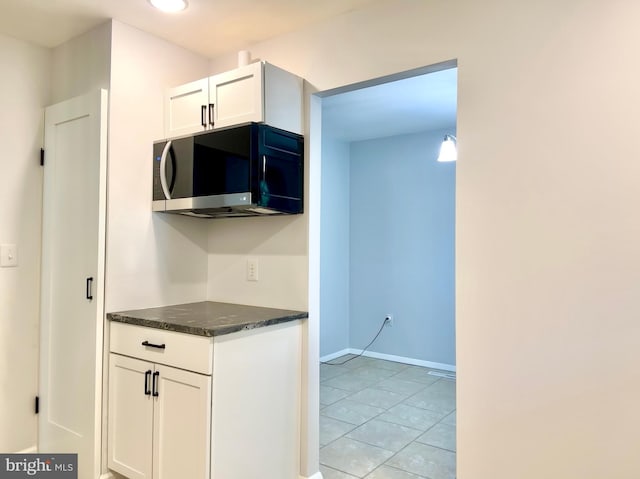 kitchen with white cabinetry, dark stone countertops, and light tile patterned floors