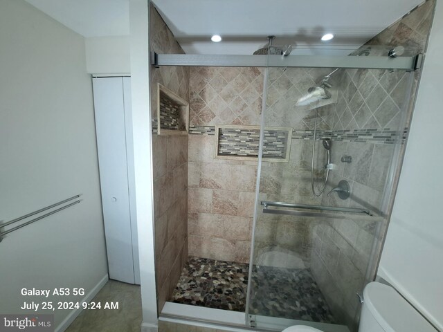 bathroom featuring toilet, an enclosed shower, and tile patterned flooring