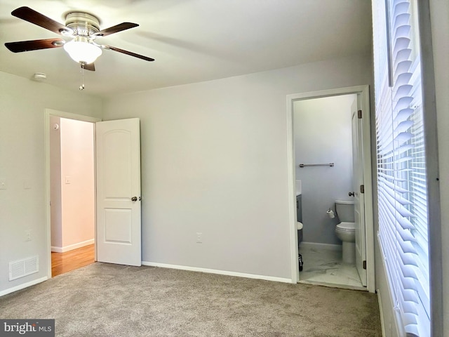 unfurnished bedroom with connected bathroom, carpet floors, and ceiling fan