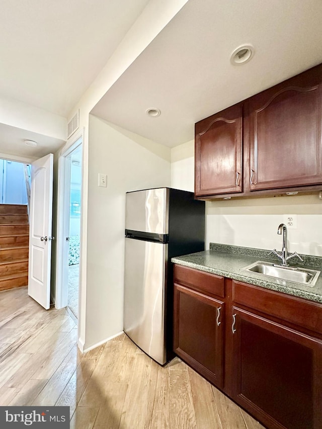 kitchen with sink, stainless steel fridge, and light hardwood / wood-style floors