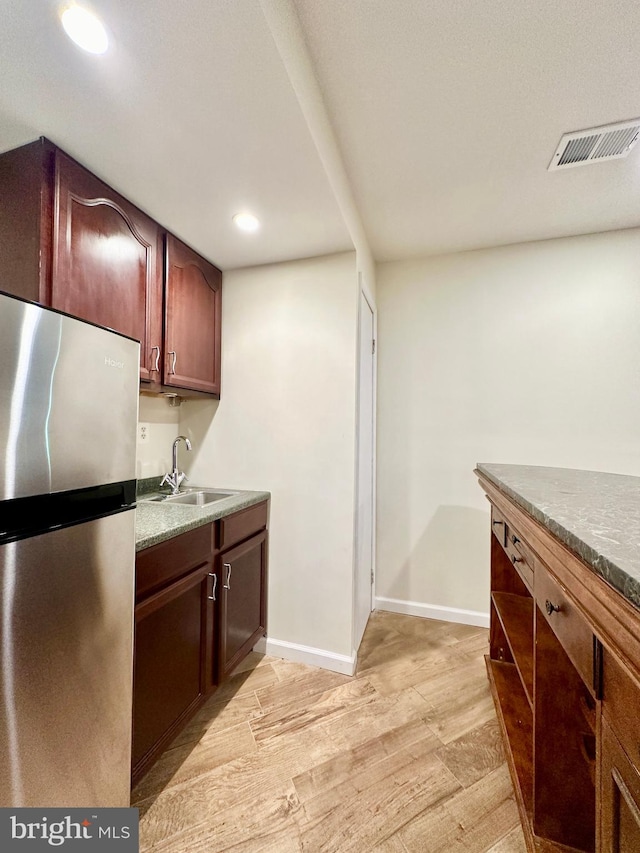 kitchen with stainless steel refrigerator, sink, and light hardwood / wood-style flooring