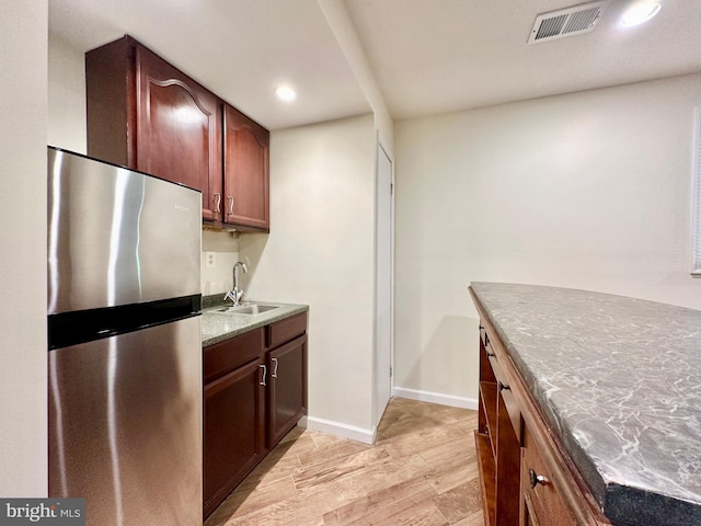 kitchen with sink, stainless steel fridge, and light wood-type flooring