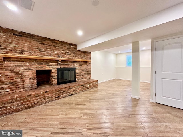 unfurnished living room featuring a brick fireplace, light hardwood / wood-style flooring, and brick wall