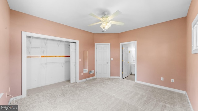 unfurnished bedroom featuring ceiling fan, light colored carpet, ensuite bathroom, and a closet