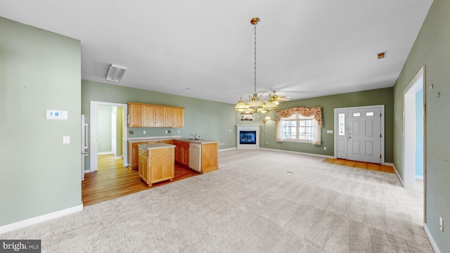 kitchen with pendant lighting, dishwasher, sink, light brown cabinetry, and light colored carpet