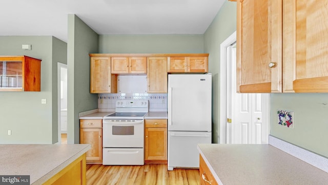 kitchen featuring light wood-type flooring, white appliances, and tasteful backsplash