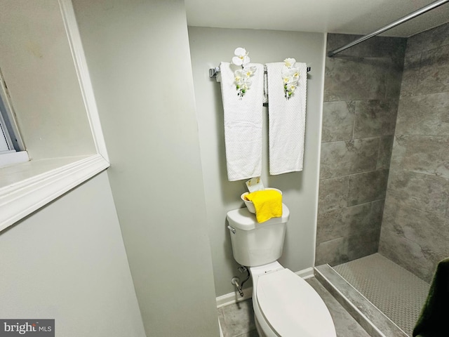 bathroom featuring tile patterned floors, toilet, and a tile shower