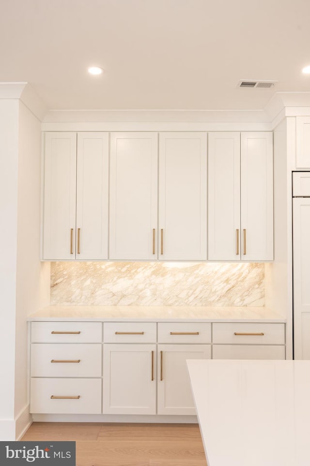 kitchen featuring decorative backsplash, light stone countertops, white cabinetry, and light wood-type flooring