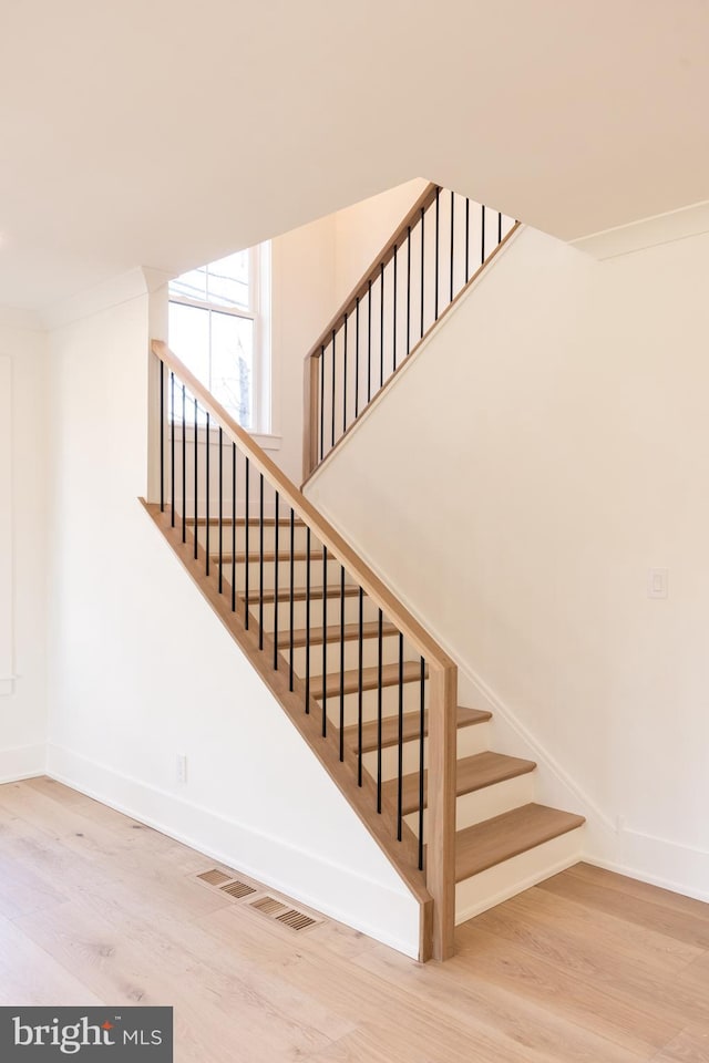 stairs with hardwood / wood-style floors and ornamental molding