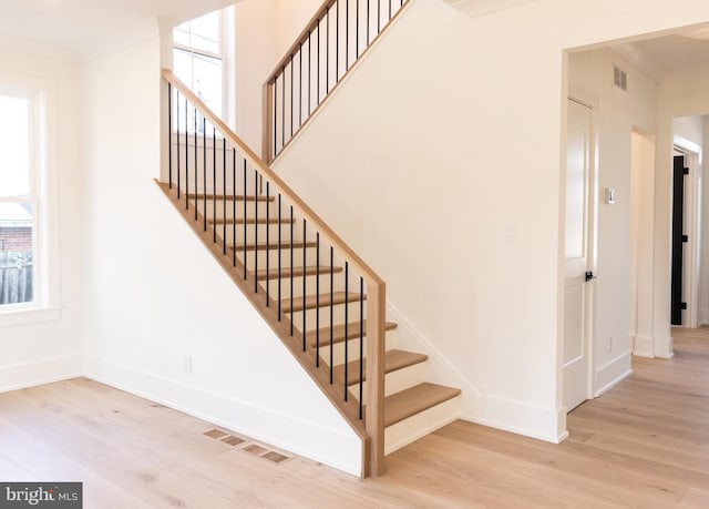 stairway featuring crown molding and wood-type flooring