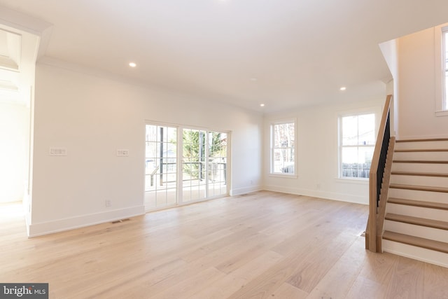 unfurnished living room featuring crown molding, plenty of natural light, and light wood-type flooring