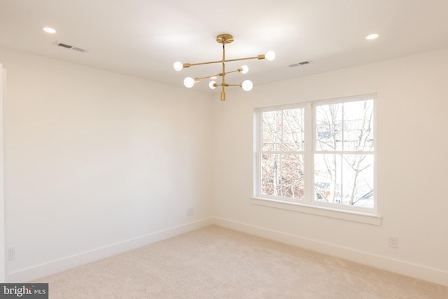 empty room featuring carpet and an inviting chandelier