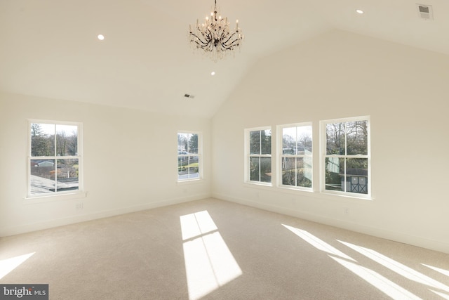 carpeted spare room with a notable chandelier and high vaulted ceiling