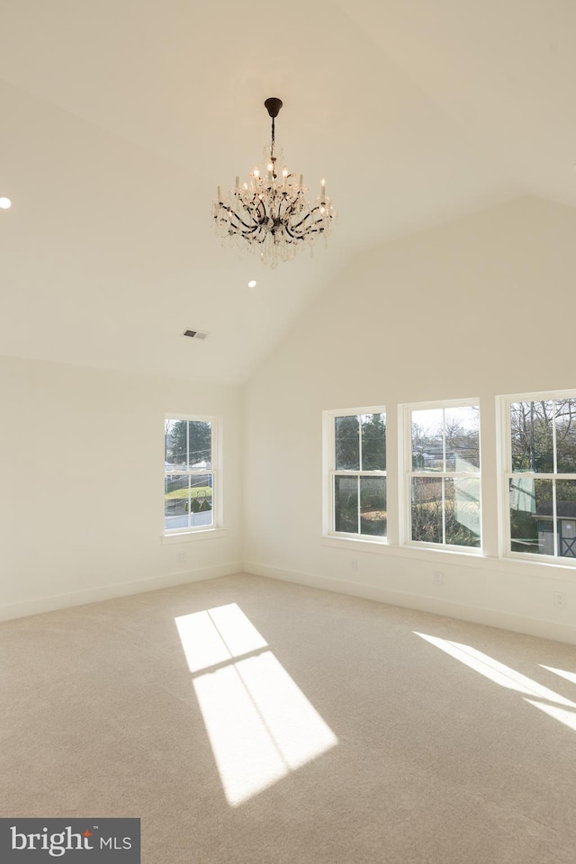 empty room with a chandelier, carpet, and vaulted ceiling