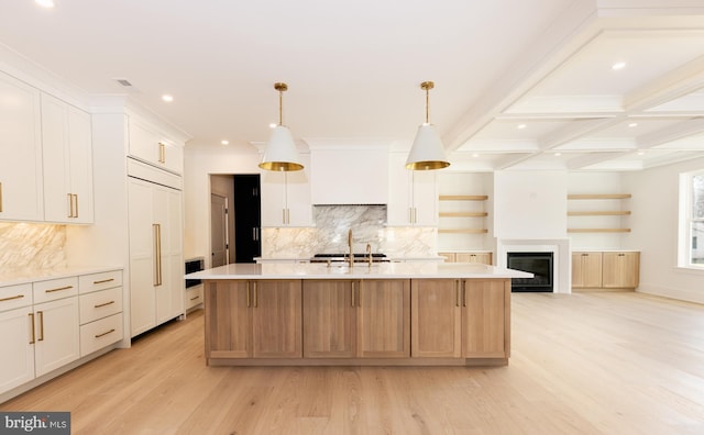 kitchen with paneled built in fridge, a spacious island, white cabinetry, and hanging light fixtures