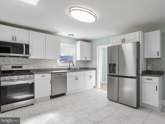 kitchen featuring stainless steel appliances, decorative backsplash, white cabinets, and sink