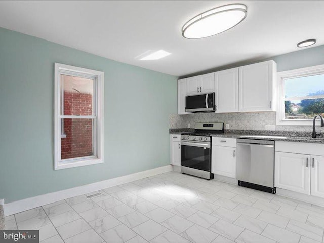 kitchen with decorative backsplash, appliances with stainless steel finishes, sink, and white cabinetry