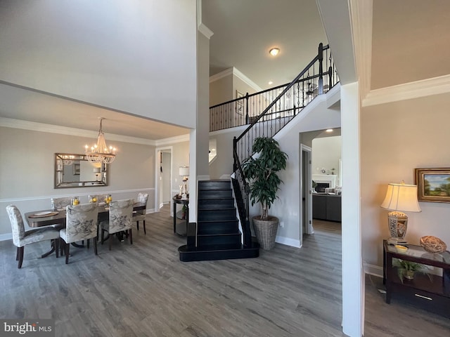 dining room featuring hardwood / wood-style floors, a notable chandelier, crown molding, and a high ceiling