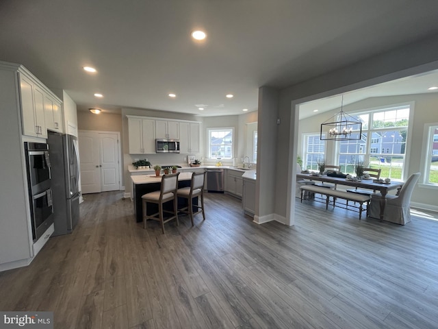 kitchen featuring a center island, dark wood-type flooring, white cabinetry, stainless steel appliances, and a chandelier