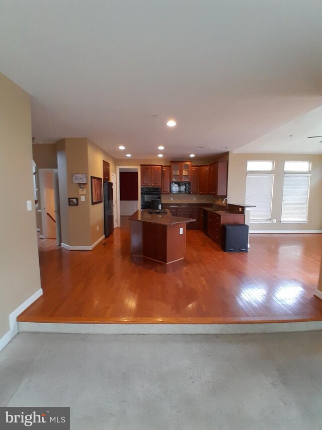 kitchen featuring a center island, black appliances, hardwood / wood-style floors, and sink