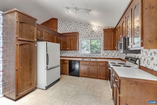 kitchen featuring a textured ceiling, white appliances, sink, and vaulted ceiling