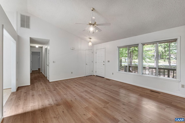 unfurnished room featuring a textured ceiling, light hardwood / wood-style flooring, vaulted ceiling, and ceiling fan